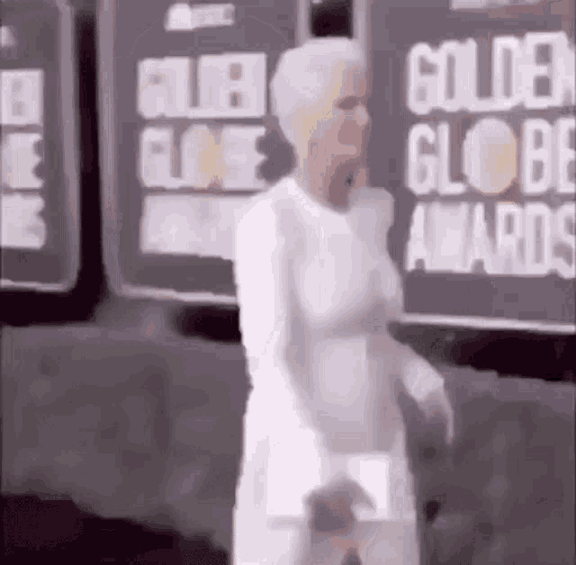 a woman in a white dress is walking down a red carpet .