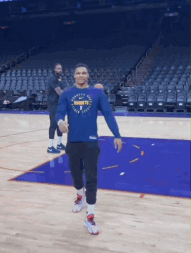 a man wearing a shirt that says nuggets walking on a basketball court
