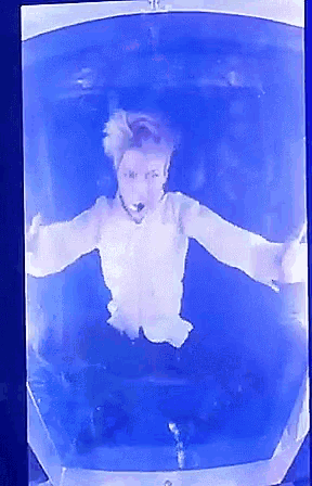 a person in a white shirt is floating in a blue liquid