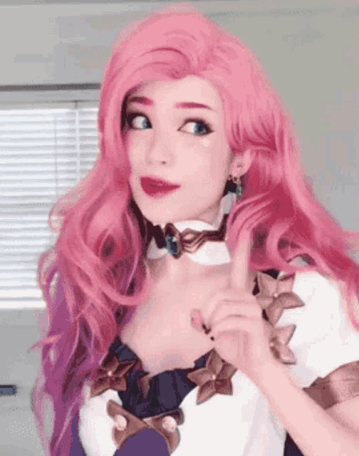 a woman with pink hair is wearing a choker and giving a thumbs up .