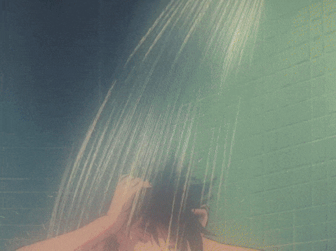 a man taking a shower with a green tile wall behind him