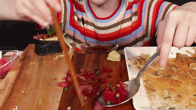 a person is holding a spoon over a plate of food on a wooden table .