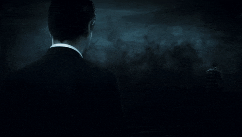 a man in a tuxedo is standing in the dark