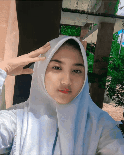 a girl wearing a white hijab is taking a picture of herself