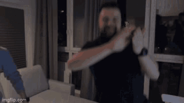 a man with a beard is clapping his hands in a room .