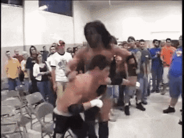 a group of people are watching a wrestling match between two men