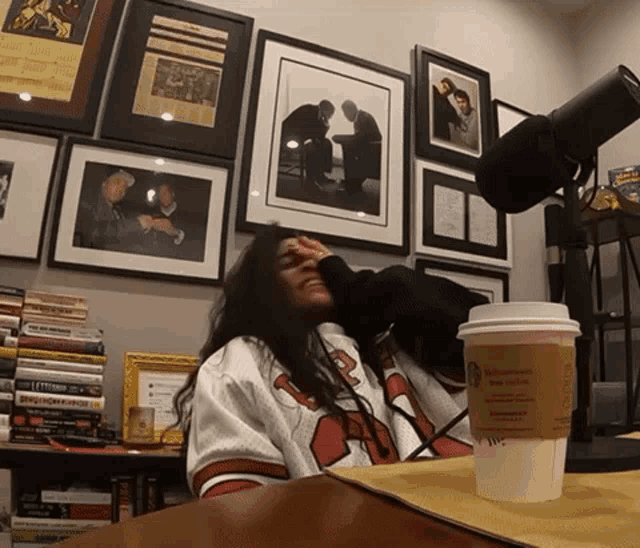 a person sitting at a table with a starbucks coffee cup in front of them