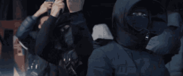a group of people wearing black hoodies and masks