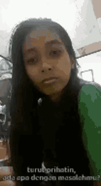 a woman with long hair is wearing a green shirt .