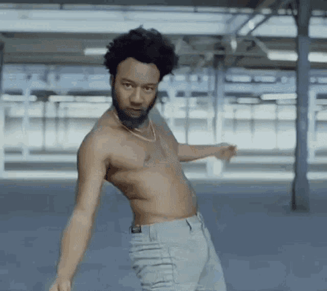 a shirtless man with a beard is dancing in a building .