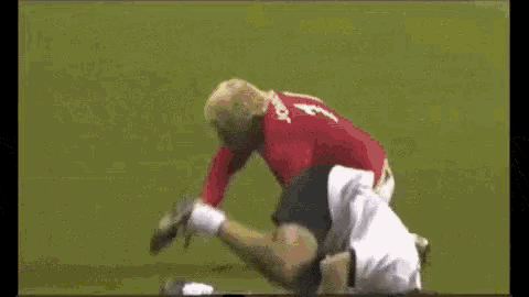 a man in a red shirt and white shorts is running on a soccer field with a soccer ball .