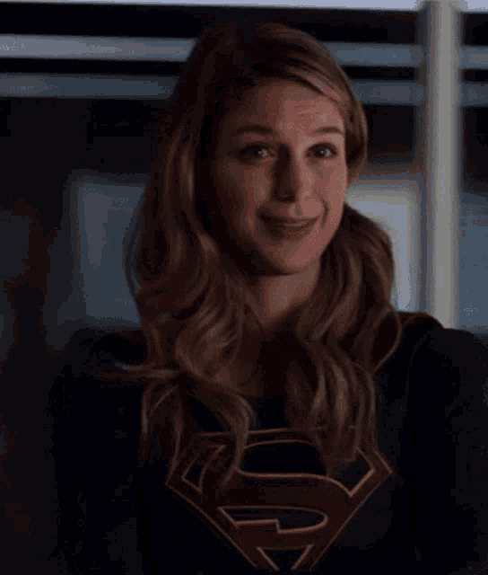 a woman in a superman costume is smiling and winking