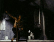 a man without a shirt is standing in a dark room