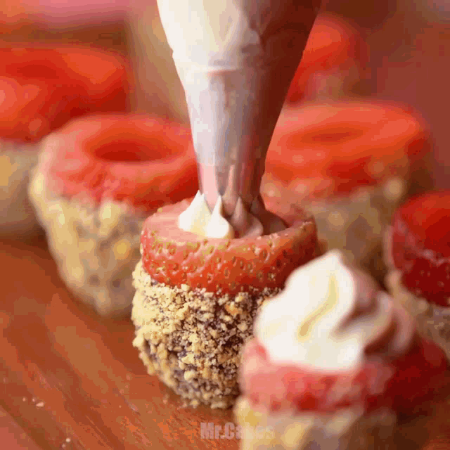strawberries are being decorated with whipped cream and nuts by mr.cakes