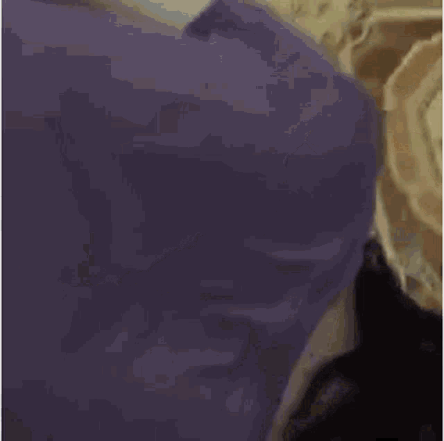 a close up of a person laying on a bed with a purple blanket .