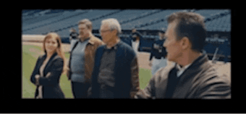 a group of people standing on a baseball field .