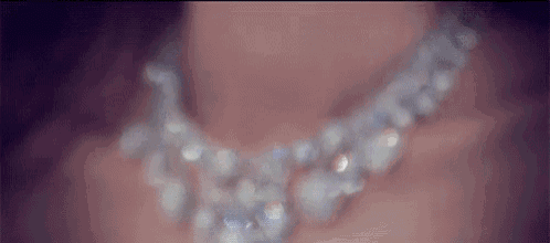 a close up of a woman wearing a necklace of pearls .