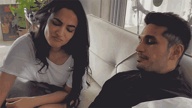 a man and a woman are sitting on a couch with a poster on the wall that says ' rock '