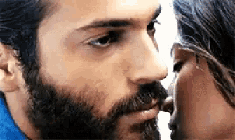 a man with a beard and a woman with long hair are kissing each other .