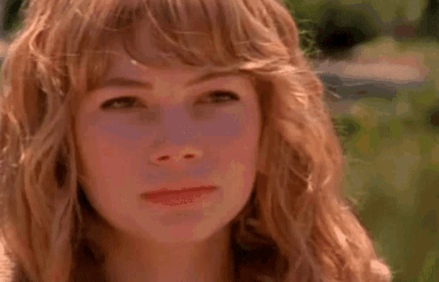 a close up of a woman 's face with long red hair and bangs .