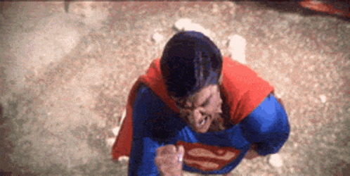 a man in a superman costume is standing on a rocky surface .
