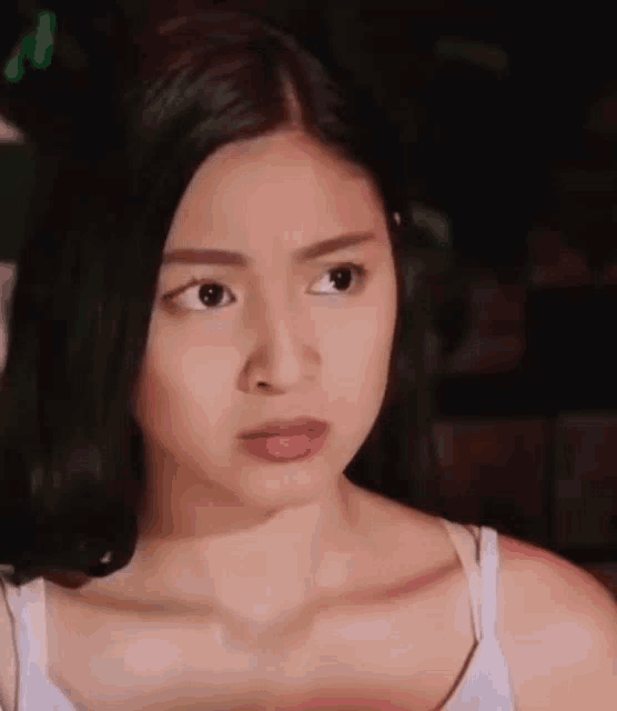 a woman is making a funny face and looking at the camera .