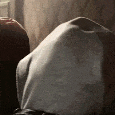 a person is laying on a couch with a white shirt on their back .