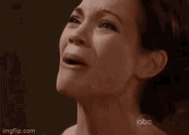 a woman is crying and covering her face with her hands .