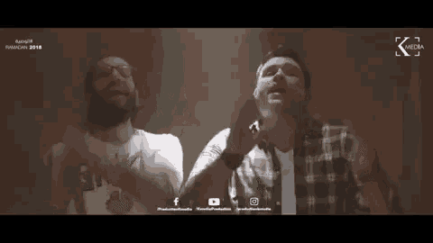two men are standing next to each other in a room and singing .
