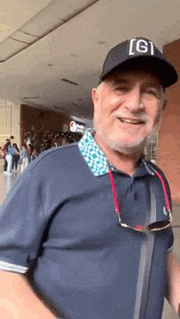 a man wearing a hat and sunglasses is smiling and looking at the camera .