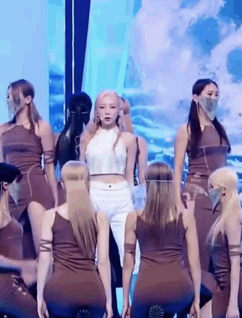 a group of women are dancing on a stage wearing face masks .