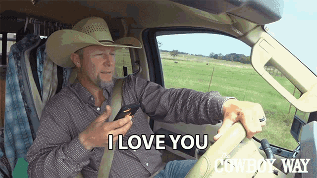 a man in a cowboy hat is driving a truck and says " i love you " on his phone