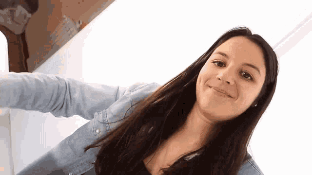 a woman in a denim jacket is smiling and looking at the camera