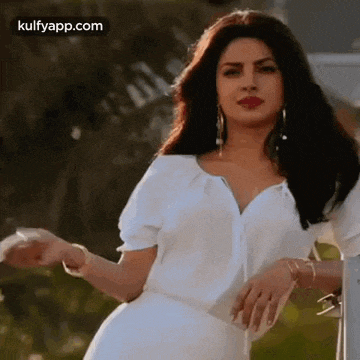 a woman in a white dress is standing next to a fence .