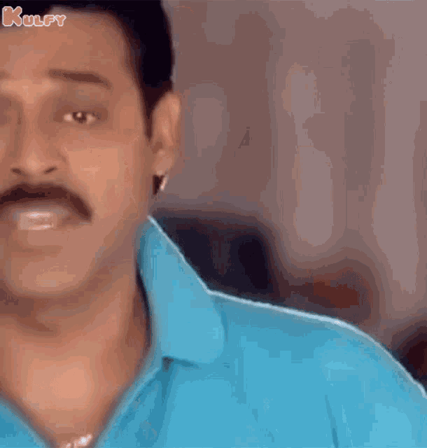 a man with a mustache is wearing a blue shirt