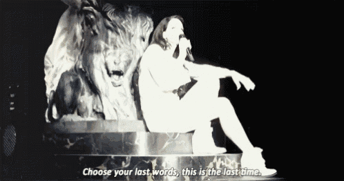 a woman is sitting in front of a statue of a lion and singing into a microphone ..