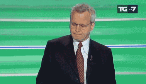 a man in a suit and tie is standing in front of a green background with the letters tg on it