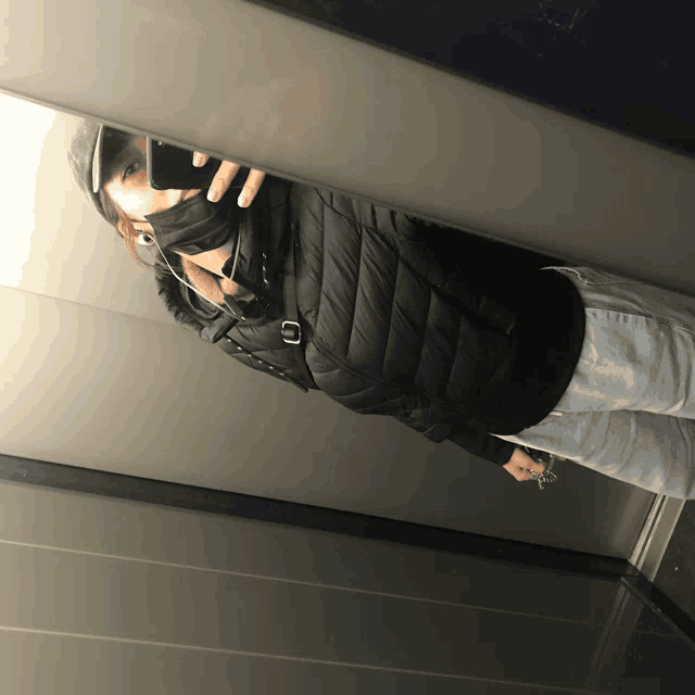 a person taking a selfie in an elevator wearing a mask