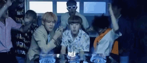 a group of young men are sitting around a table with a candle in it .