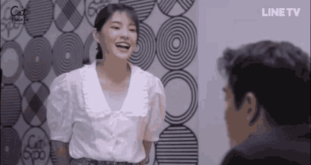 a woman in a white shirt is laughing while standing next to a man in a black shirt .