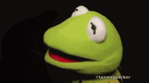 a kermit the frog puppet with its mouth open on a black background