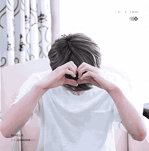a man is making a heart shape with his hands in front of his face .