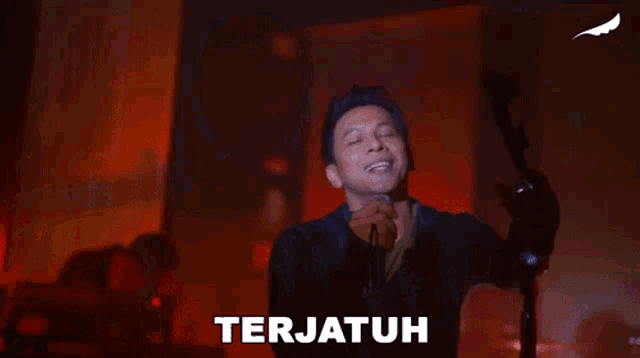 a man is singing into a microphone and the word terjauh is on the bottom