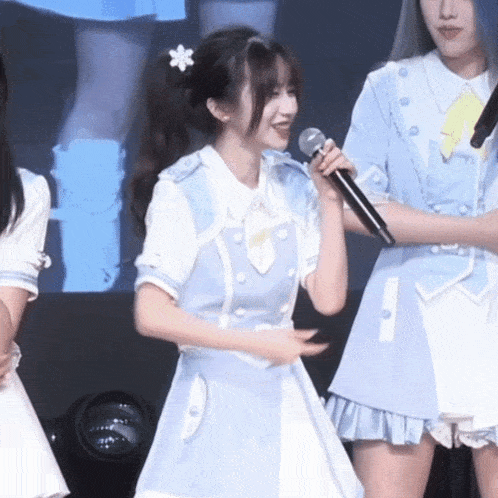 a girl in a light blue dress is holding a microphone and smiling