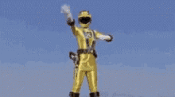 a yellow power ranger is standing in the rain with his arms in the air .