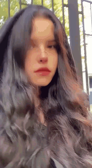 a girl with long black hair and a nose ring is wearing a black hoodie .