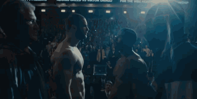 two men are standing next to each other in a dark room .