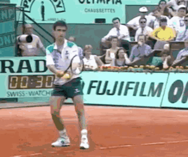 a man playing tennis in front of a fujifilm banner