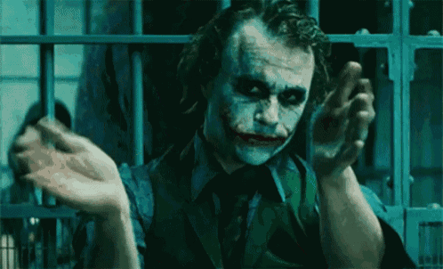 a close up of a man in a suit and tie with a joker mask on .