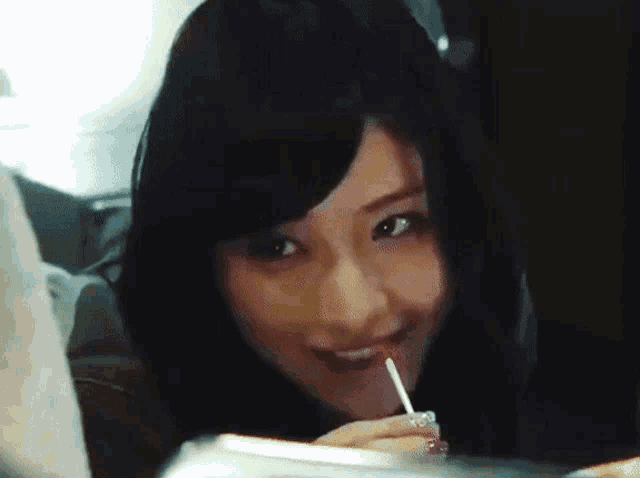 a woman is holding a lollipop in her mouth and smiling